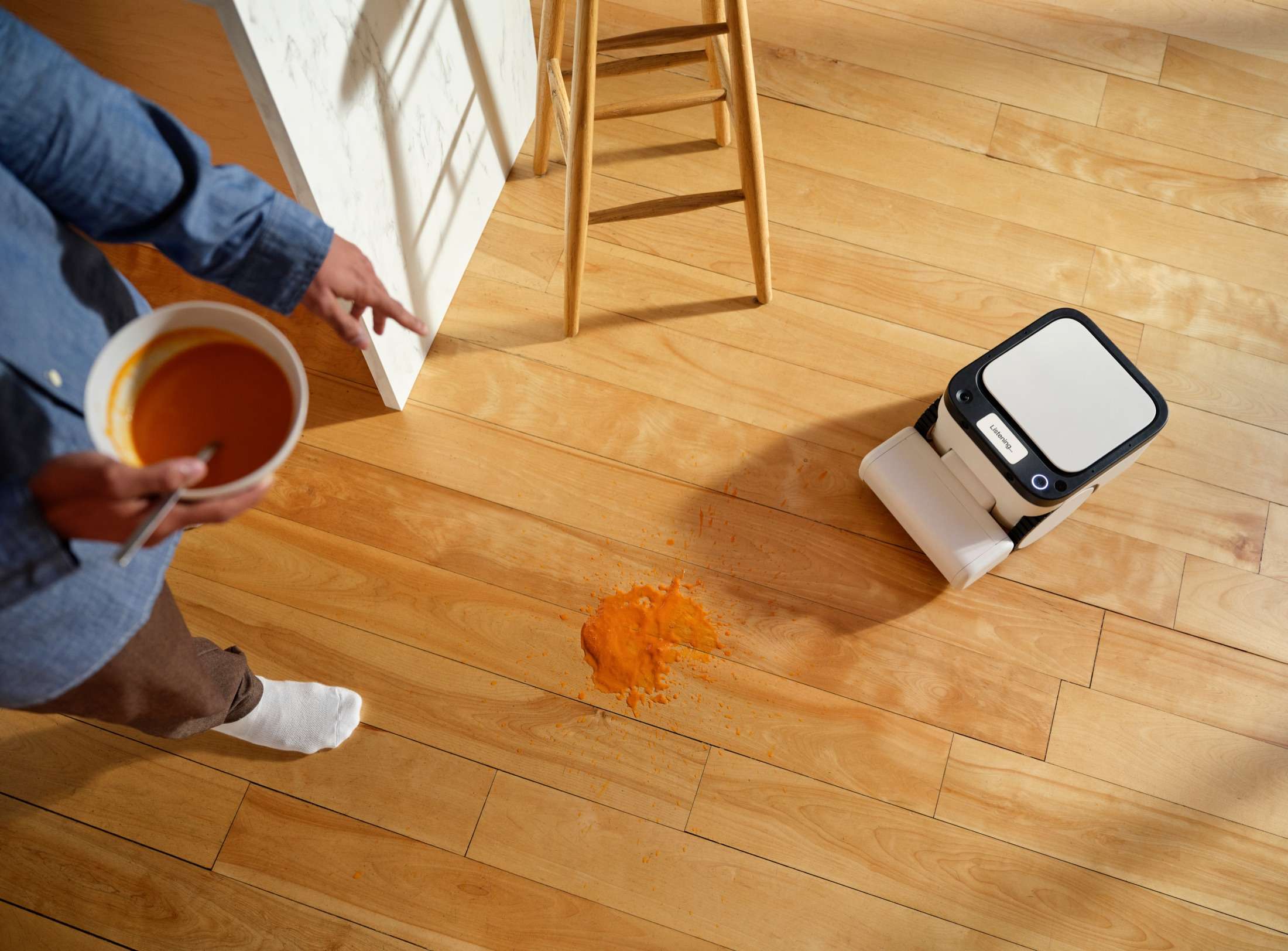 Matic robot approaching a spilled drink on a hardwood kitchen floor