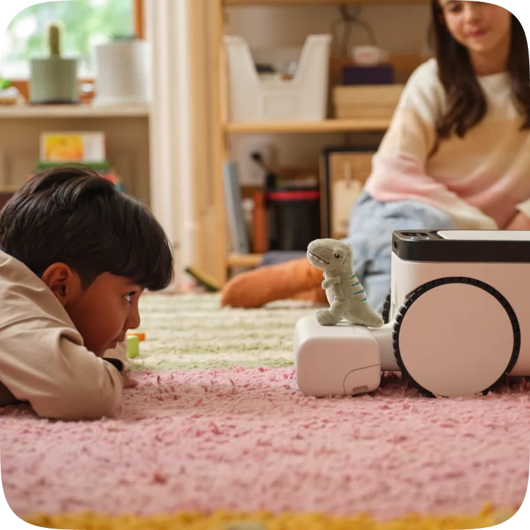 Child watching the Matic robot carry a toy dinosaur in a playroom